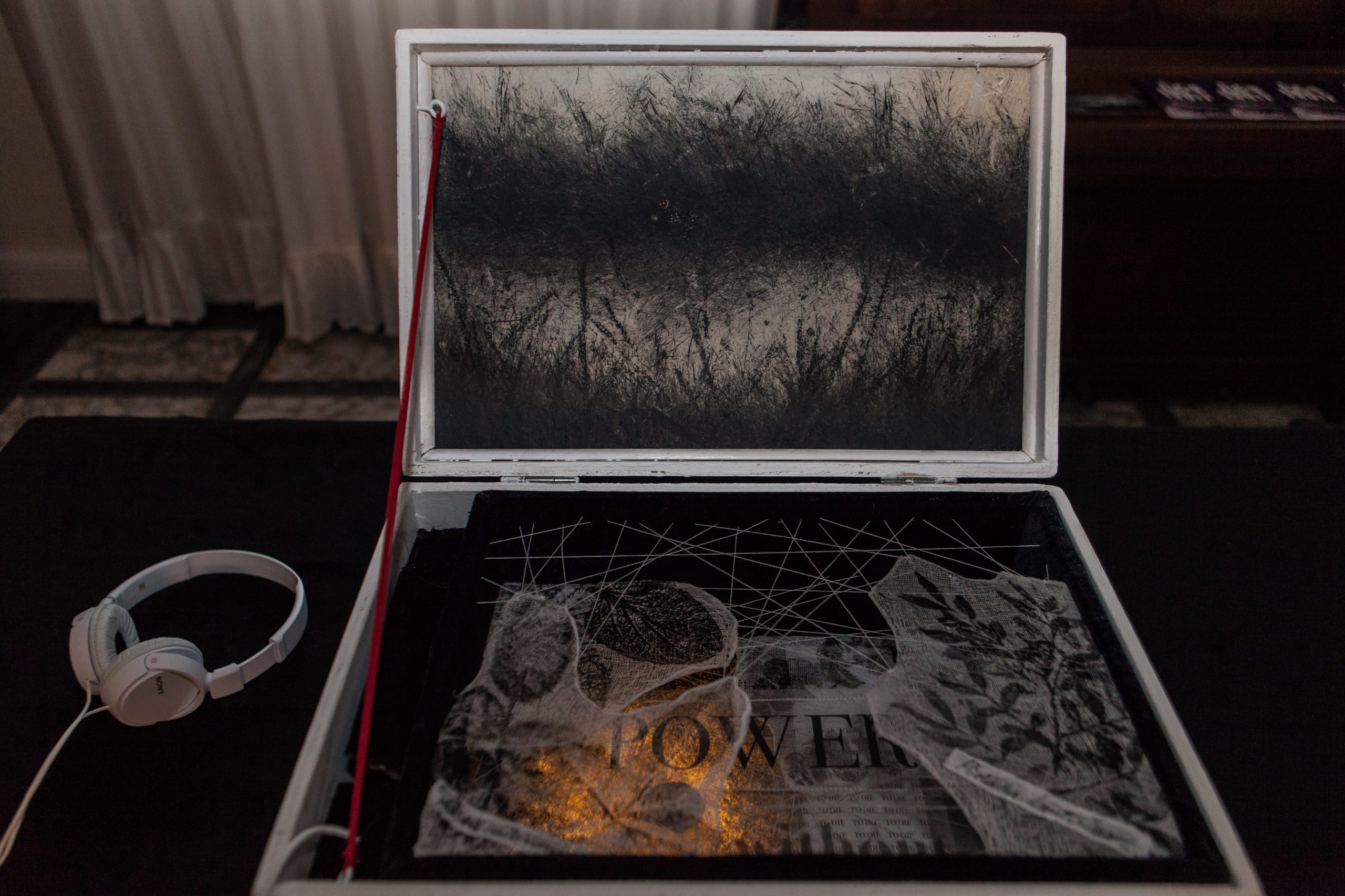 Full shot of the open chest, containing a red ribbon and a black stamps