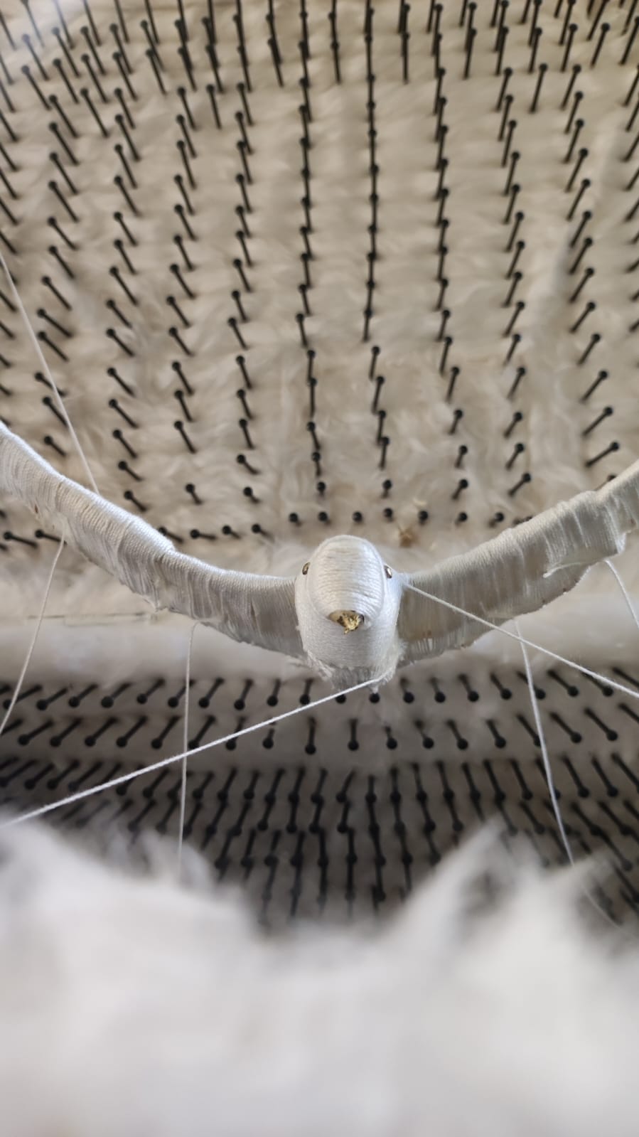 Close-up of the bird sculpture among feathers and nails.