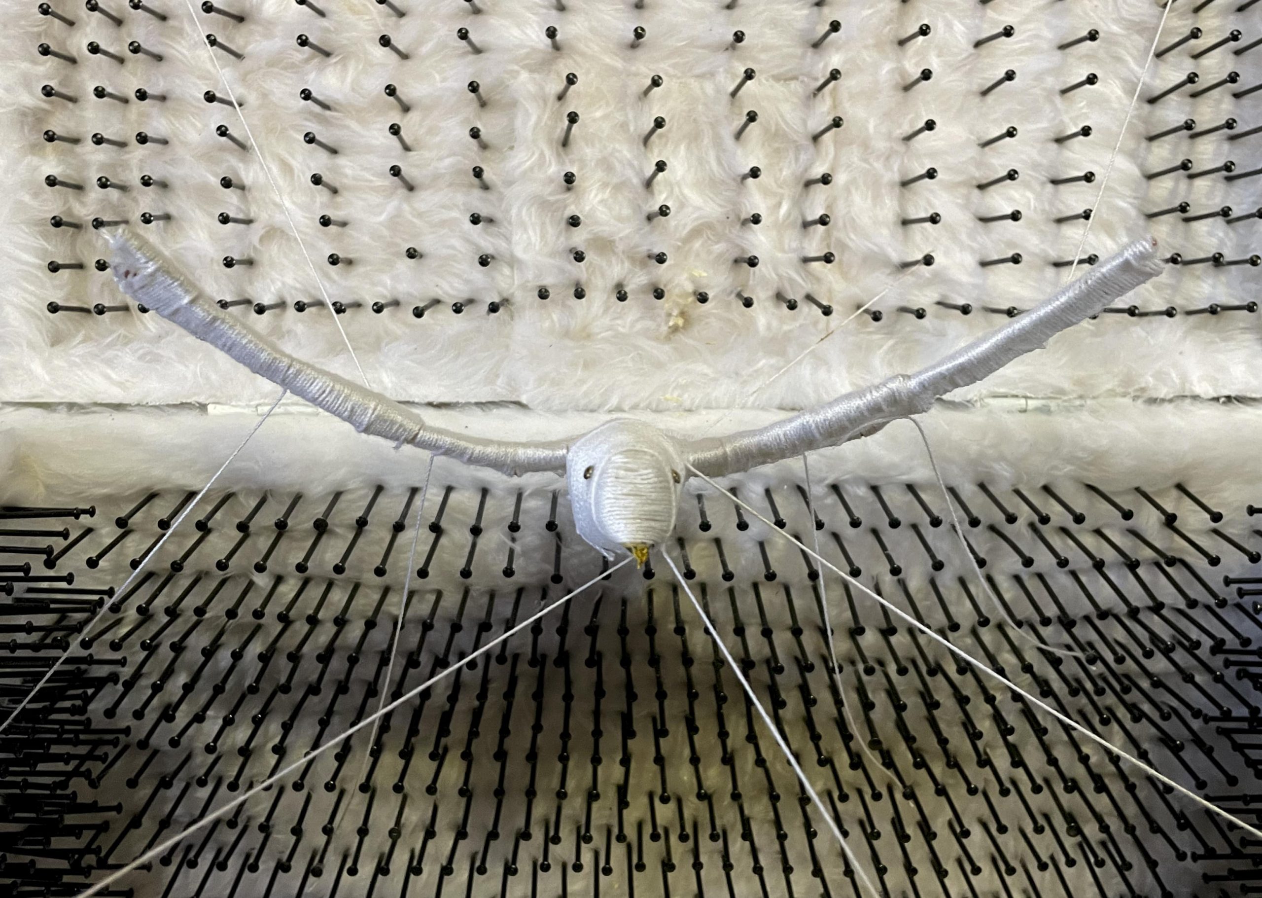 Close-up of the bird sculpture among feathers and nails.
