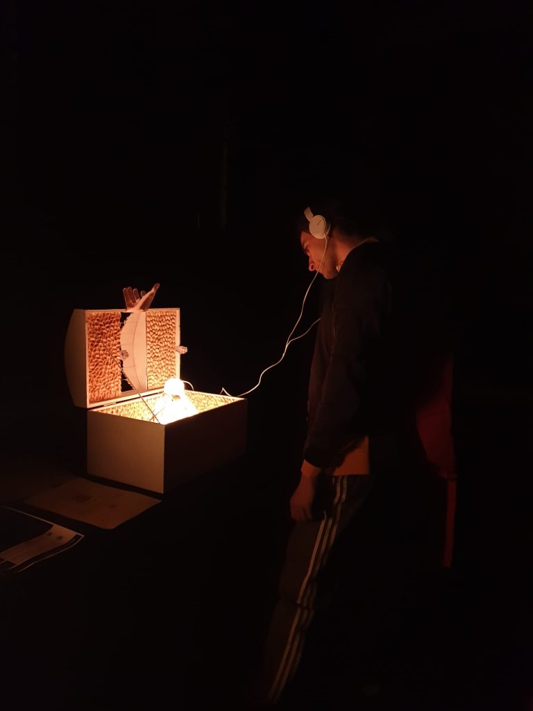 Enjoying the exhibition: a boy observing the open chest in the dark while listening to the related song through earphones connected to the chest.
